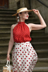 a lady in a red off the shoulder top and a white skirt with polka dots